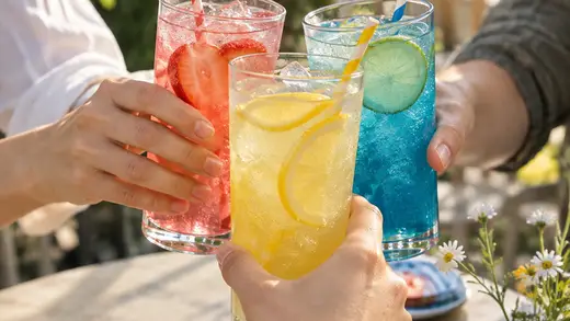 Three friends toasting with colorful fruit sodas.