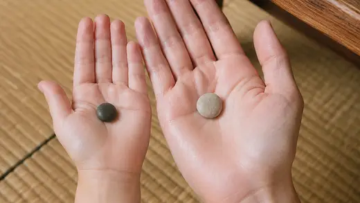 A small stone in each of an adult's and child's open palms.